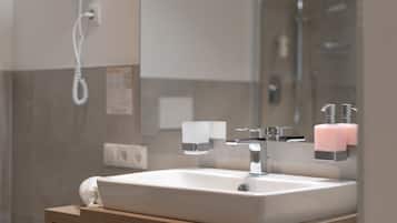 Une salle de bain avec un lavabo blanc, un miroir et un espace douche.