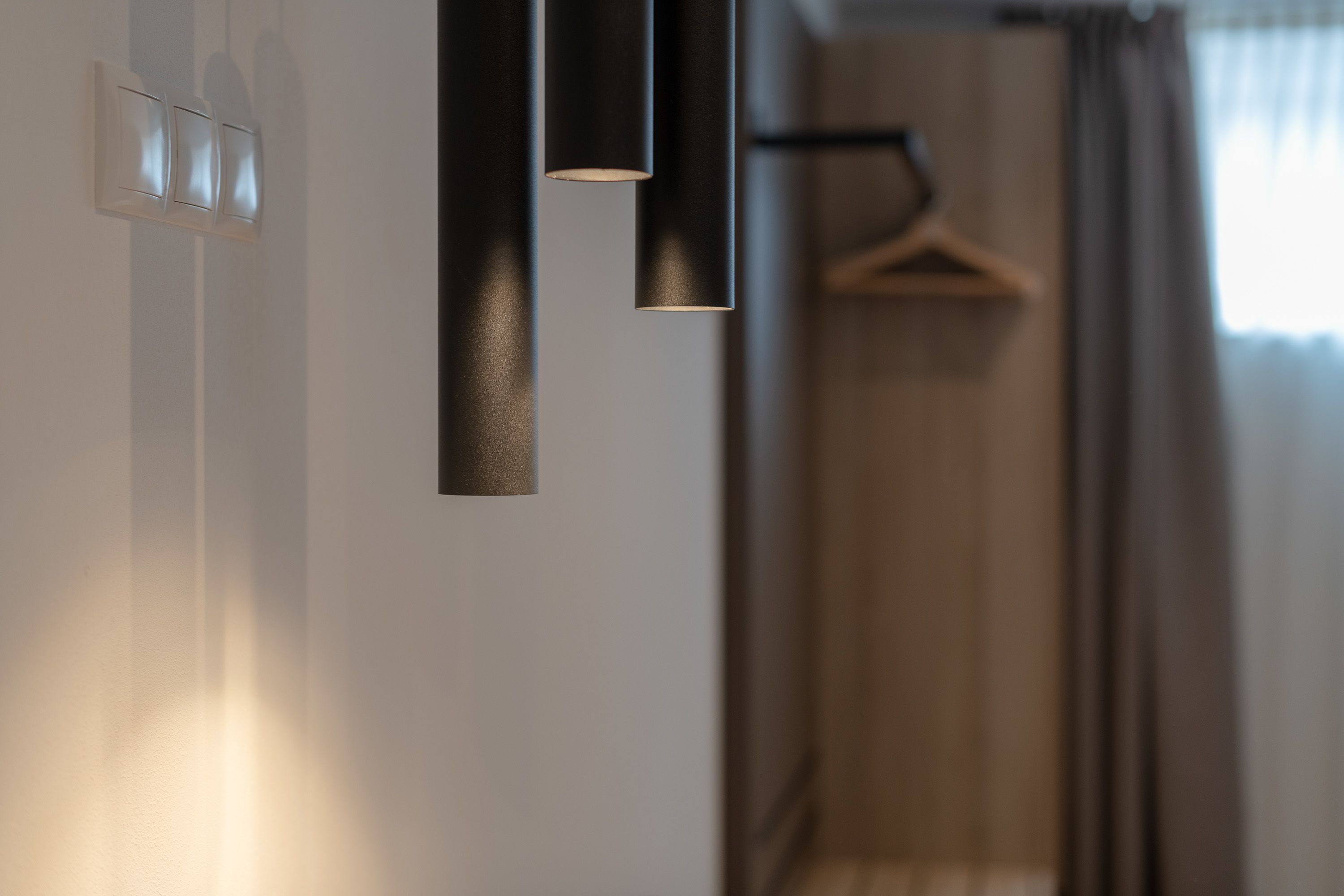 Un interior moderno con diseño minimalista, que incluye una lámpara fijada a la pared y un perchero de madera.