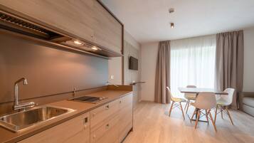 A modern kitchen with a built-in stove, a sink, and a dining area with a table and chairs.