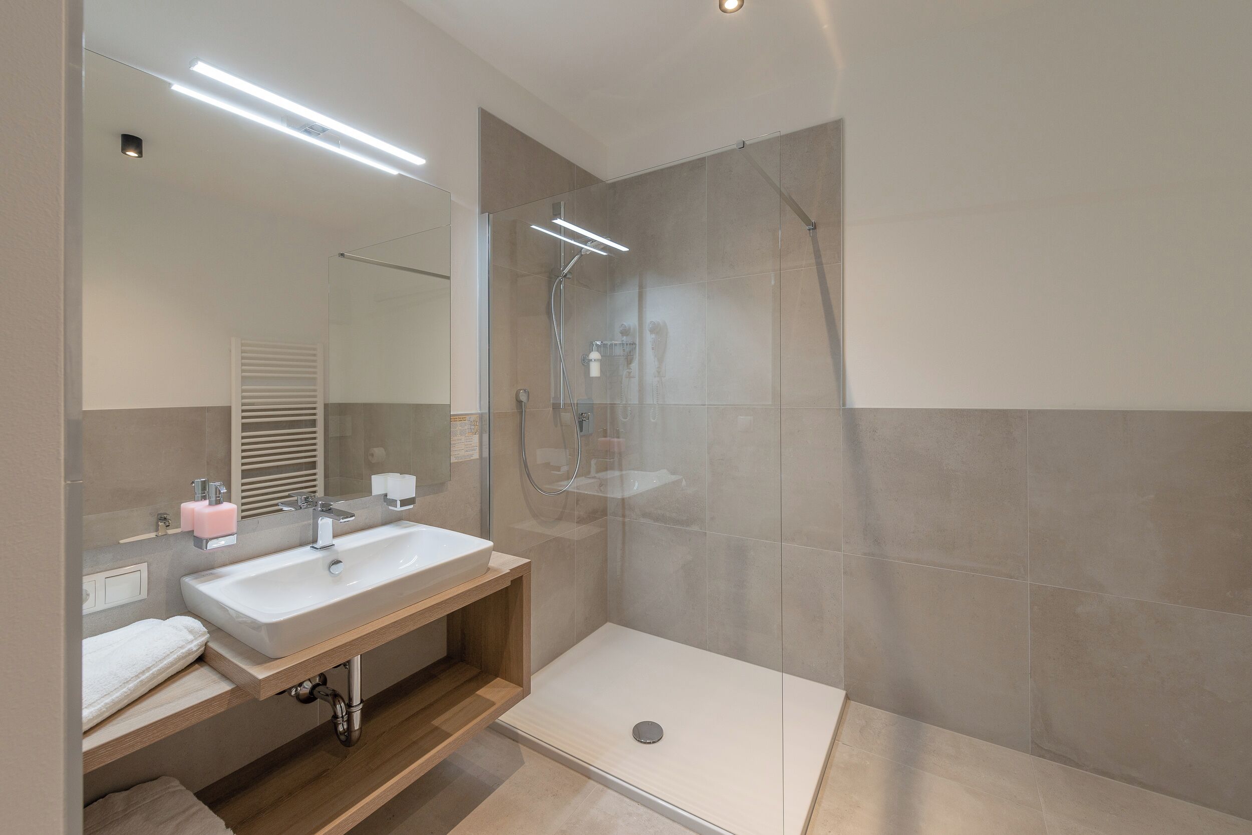 Une salle de bain moderne avec une douche à parois de verre, un lavabo blanc et un miroir.