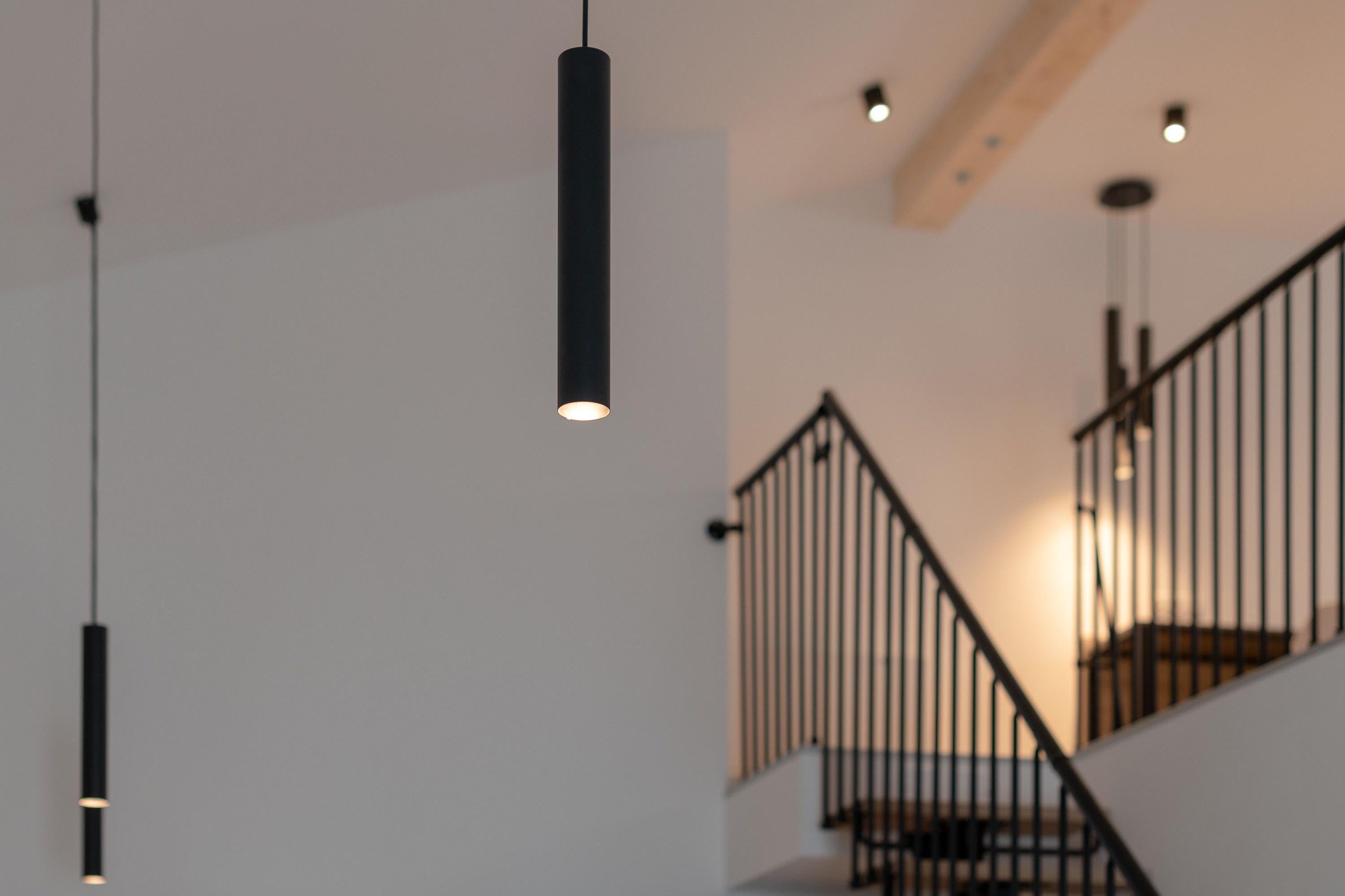 Una escalera moderna con barandilla de metal y lámparas colgantes.