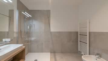 A modern bathroom with a glass-enclosed shower, a wooden vanity, and a white sink.