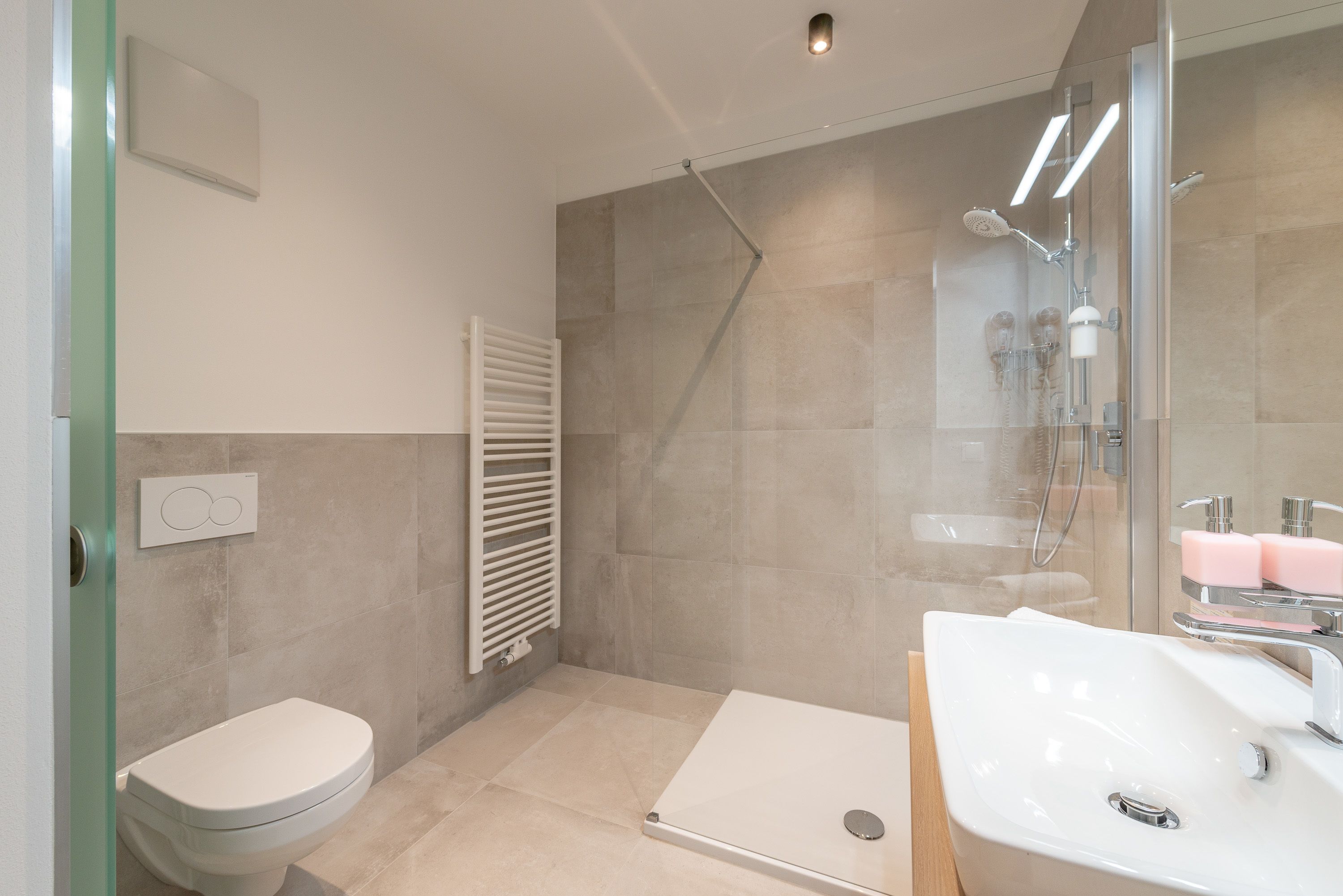 Een moderne badkamer met een douche, toilet en wastafel.