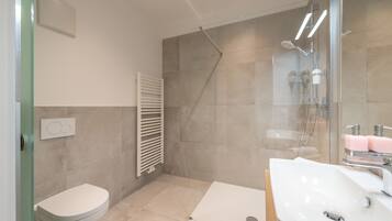 Een moderne badkamer met een douche, toilet en wastafel.