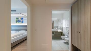 Une chambre moderne avec un lit, une table de chevet et une bouche d’aération fixée au mur.