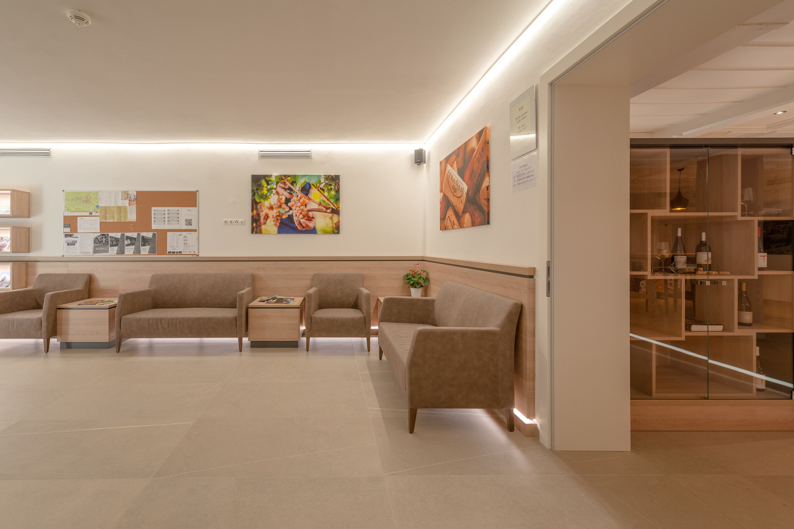 A modern lobby with sofas, a reception desk, and a wine display.