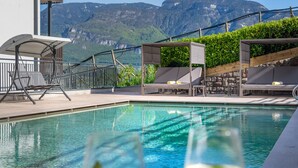 A pool area with lounge chairs and a view of mountains. - Vineus (Termeno Sulla Strada del Vino)