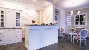 Una cocina moderna con armarios blancos, una isla central y un comedor con mesa y sillas.