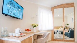 Una sala de estar moderna con televisor, un área de cocina con mostrador, una silla y un espejo grande.