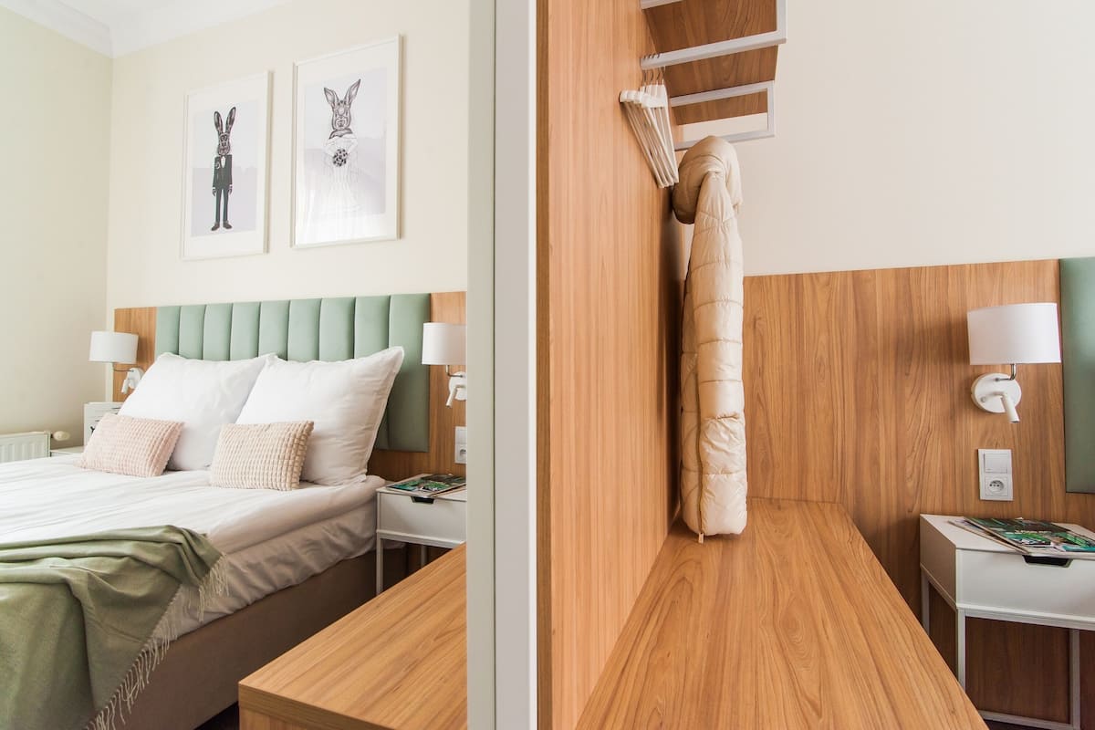 A hotel room with a bed, bedside tables, a wooden headboard, and artwork on the wall.