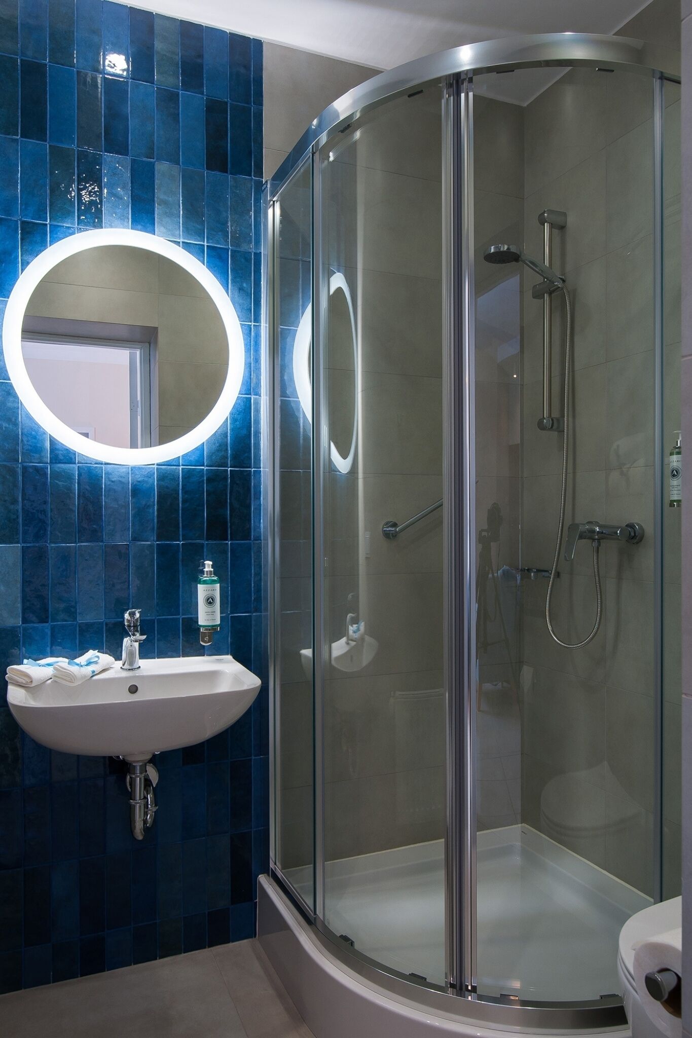 A modern bathroom with a glass-enclosed shower, a white sink, and a blue-tiled wall.