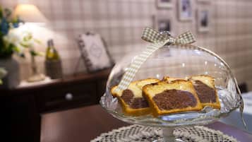 A glass dome cake stand with a checkered ribbon on a lace doily.