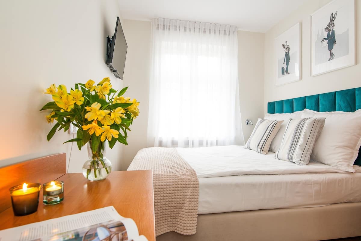 A neatly arranged bedroom with a bed, bedside table, and a vase of yellow flowers.