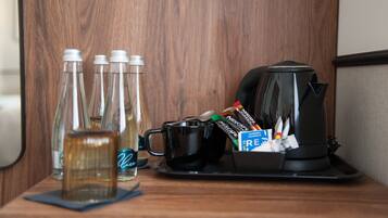 A wooden table with a coffee maker, a tray with a black mug, and several glass bottles.