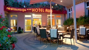 Un hotel con terraza, una zona de recepción y un letrero de neón que indica que es restaurante y hotel.