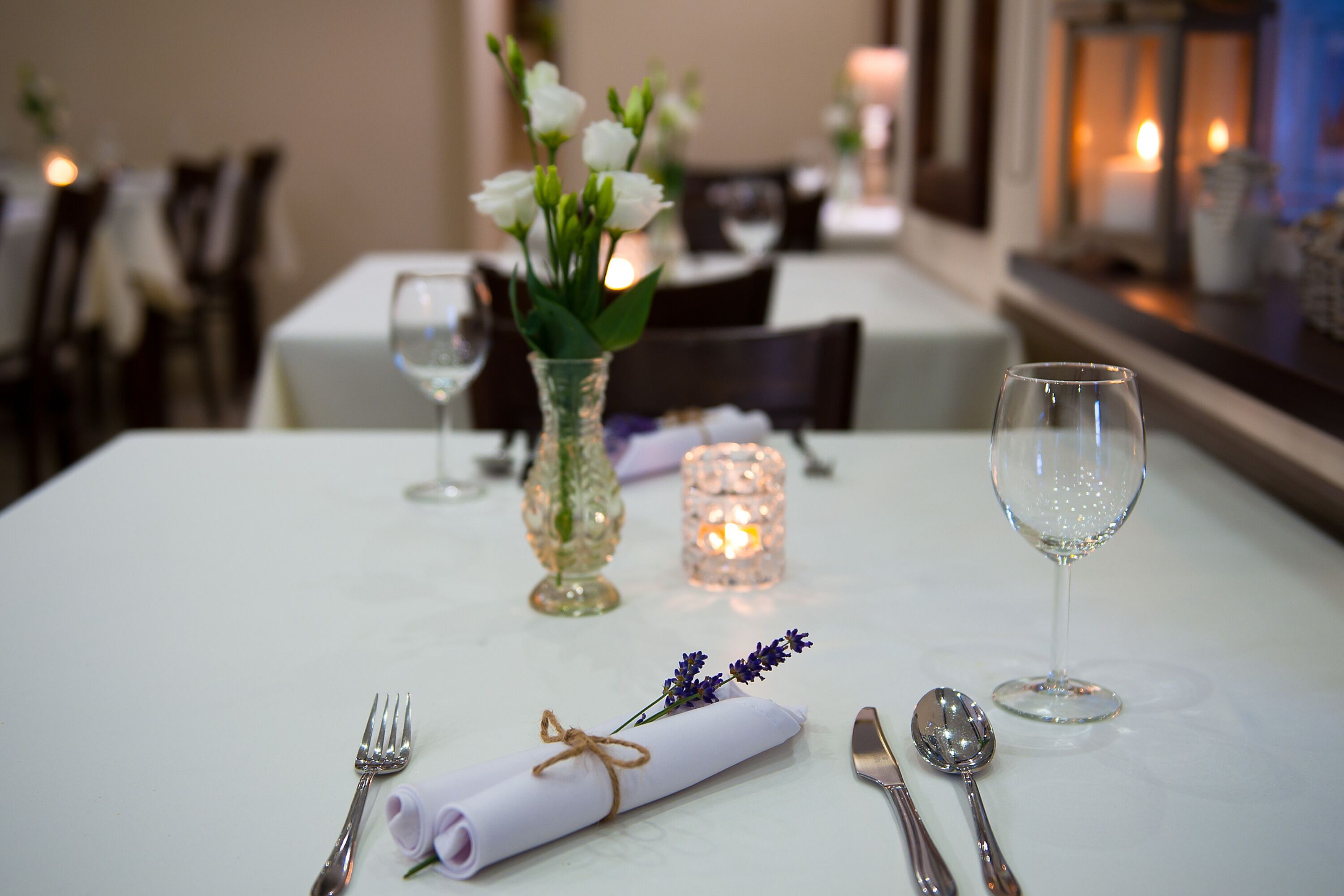 A neatly set dining table with a folded napkin, silverware, and a glass of water.