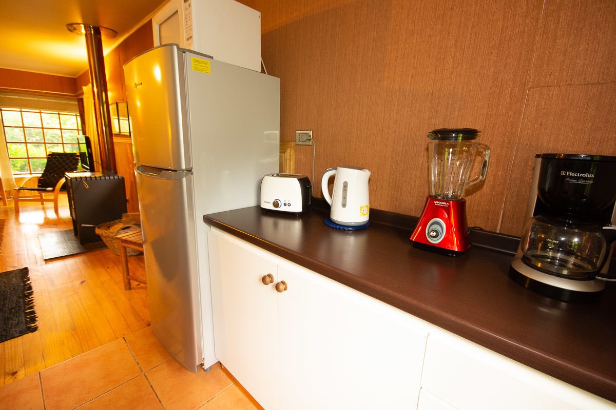 Eine Küche mit Kühlschrank, Toaster, Wasserkocher, Mixer und Kaffeemaschine auf der Arbeitsfläche.