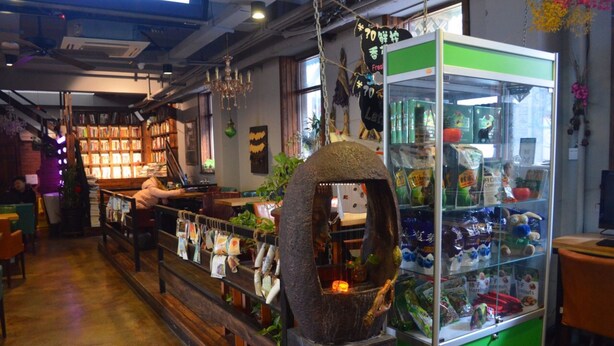 Una librería con estanterías llenas de libros, un expositor de aperitivos y una estructura decorativa de piedra.