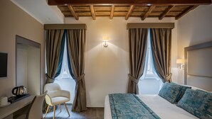 Una habitación de hotel con cama, escritorio con silla, televisión y ventana con cortinas.