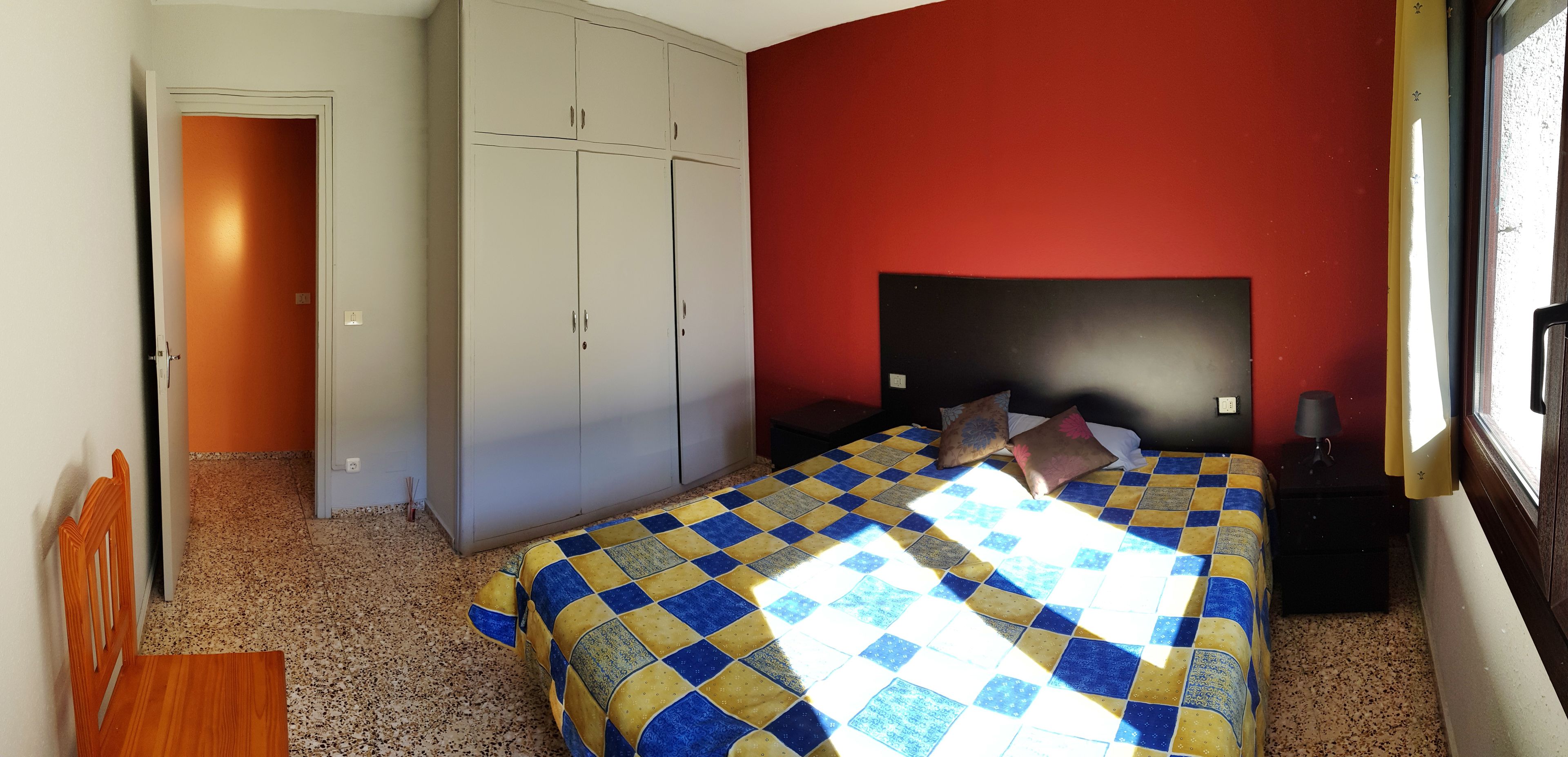 A bedroom with a bed, a wardrobe, a nightstand, and a window.