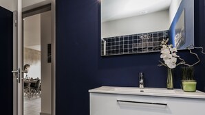A modern bathroom with a white vanity, a mirror, and a potted orchid. - Innapartments - Passos Manuel (Porto)