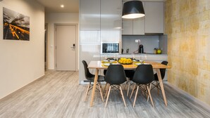 A modern kitchen with a dining area, featuring a wooden table, black chairs, and a pendant light. - Innapartments - Passos Manuel (Porto)
