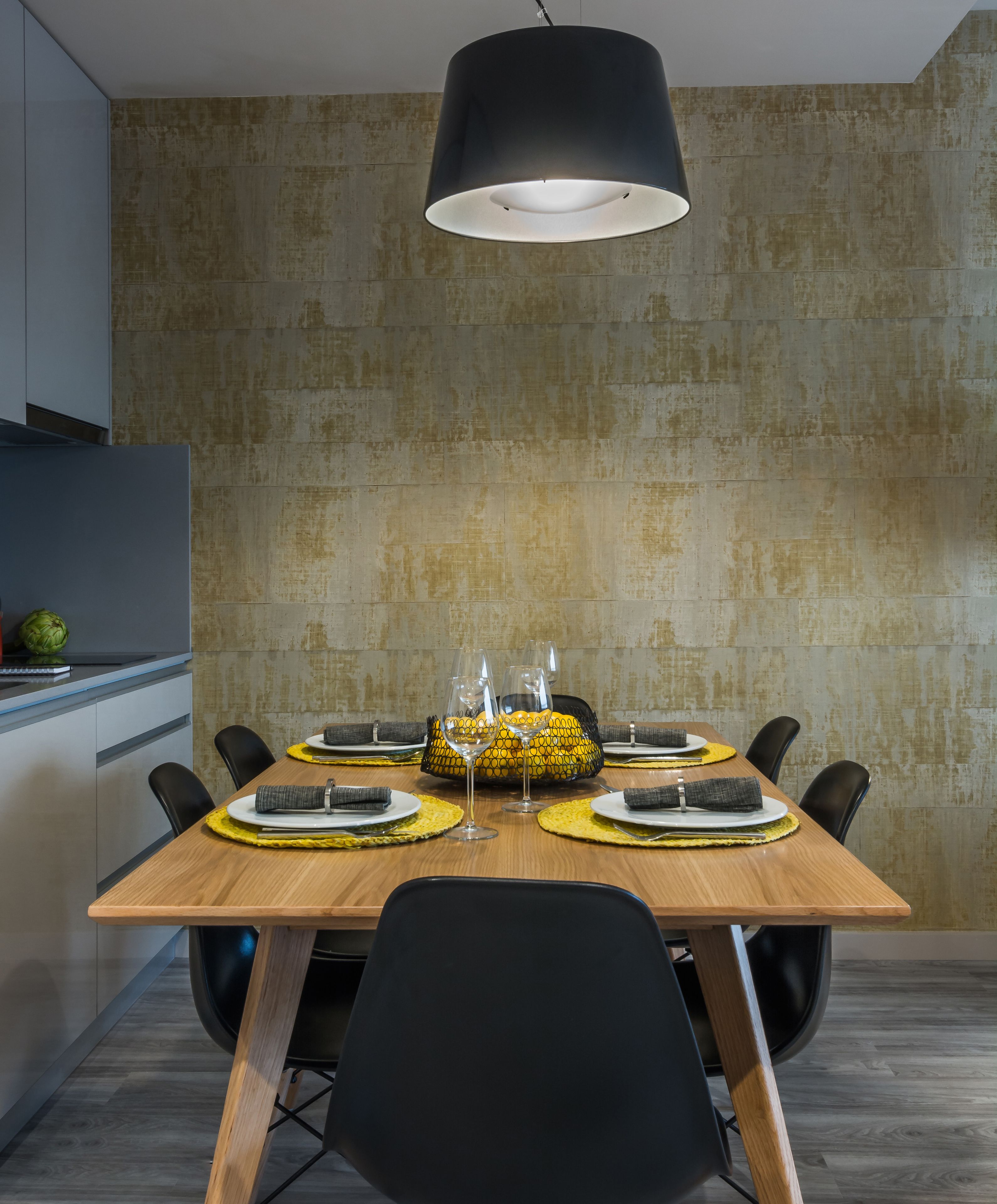 A modern dining area with a wooden table set for four, black chairs, and a black pendant light.