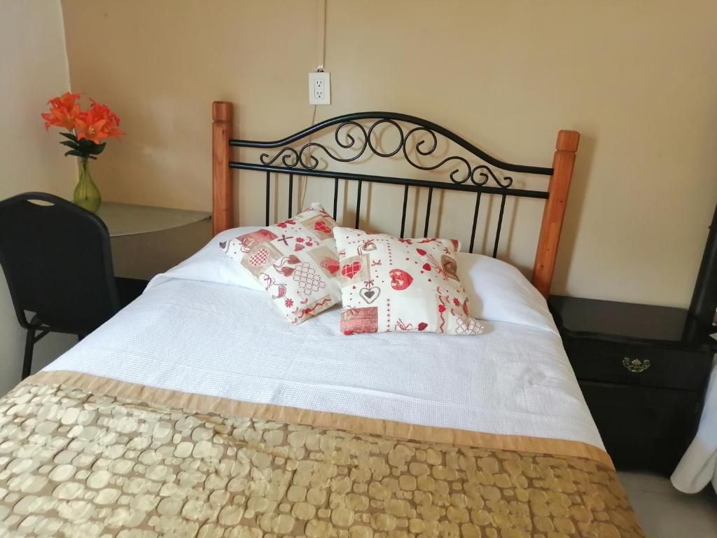 A bed with a patterned bedspread, a decorative headboard, and a bedside table with a vase of flowers.