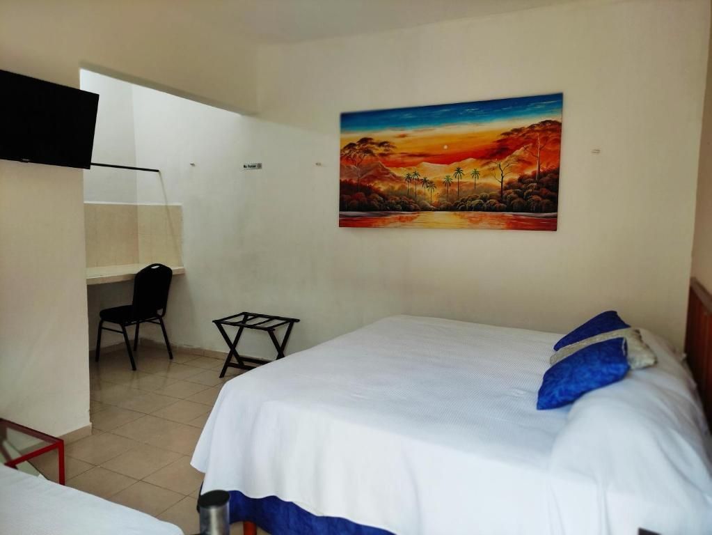 Habitación de hotel con cama, escritorio, silla y un cuadro en la pared.
