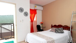 Un dormitorio con cama, una silla, un escritorio y un balcón.