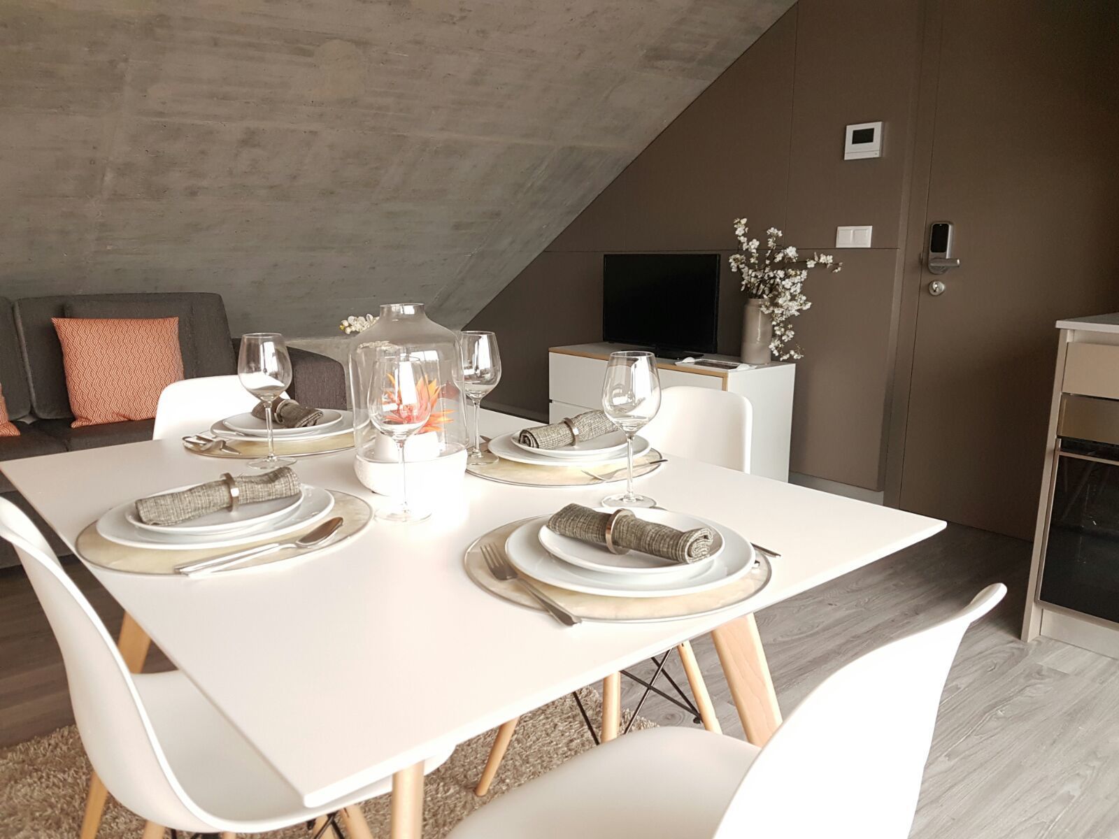 A dining area with a white table set for four, including plates, glasses, and cutlery.