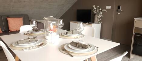A dining area with a white table set for four, including plates, glasses, and cutlery.