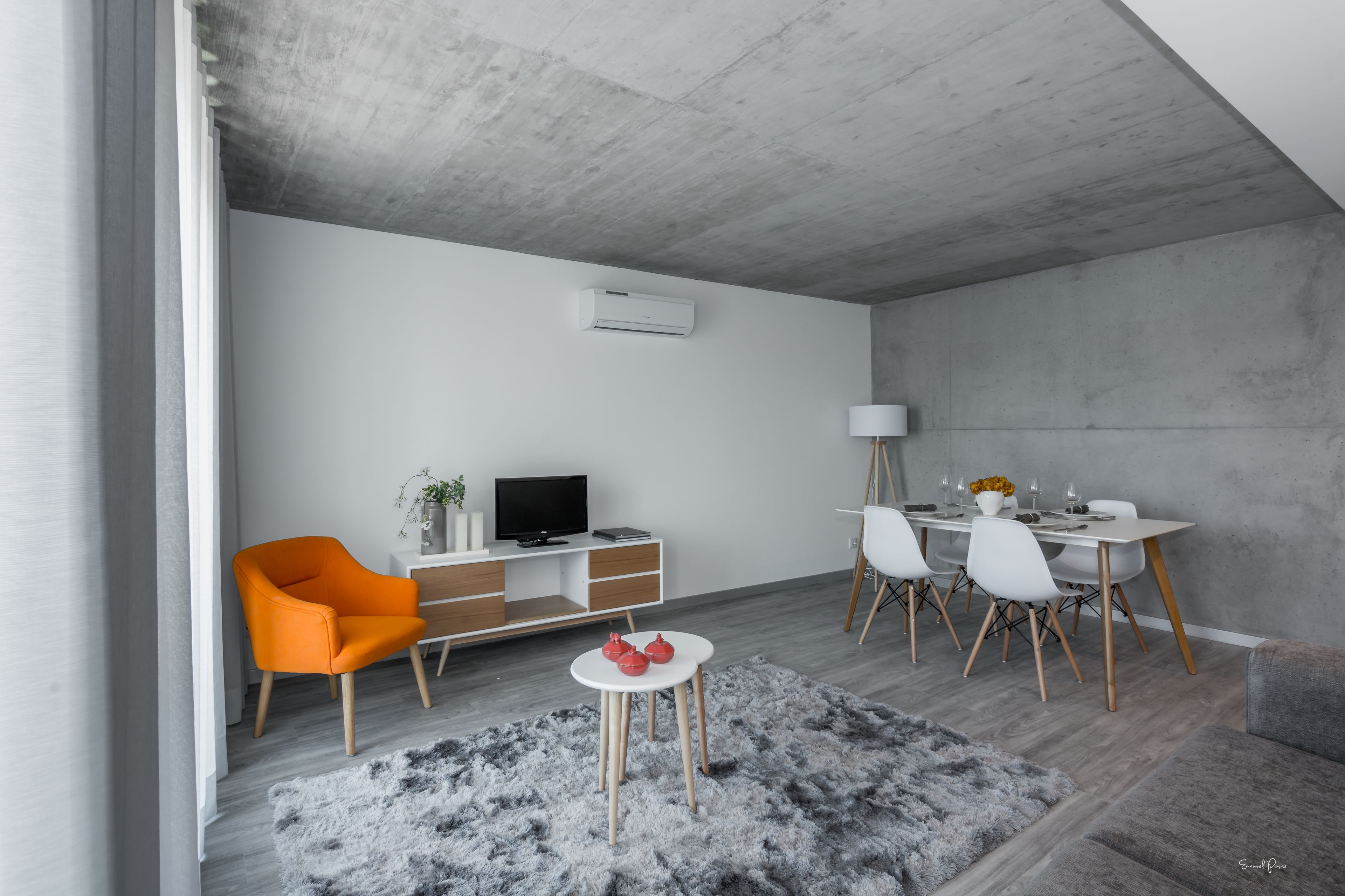 Una sala de estar moderna con comedor, un sofá, una mesa de centro y un televisor sobre un mueble de madera.