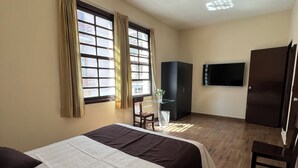 A hotel room with a large bed, a TV mounted on the wall, and a wardrobe. - Hotel Tito (Arequipa)