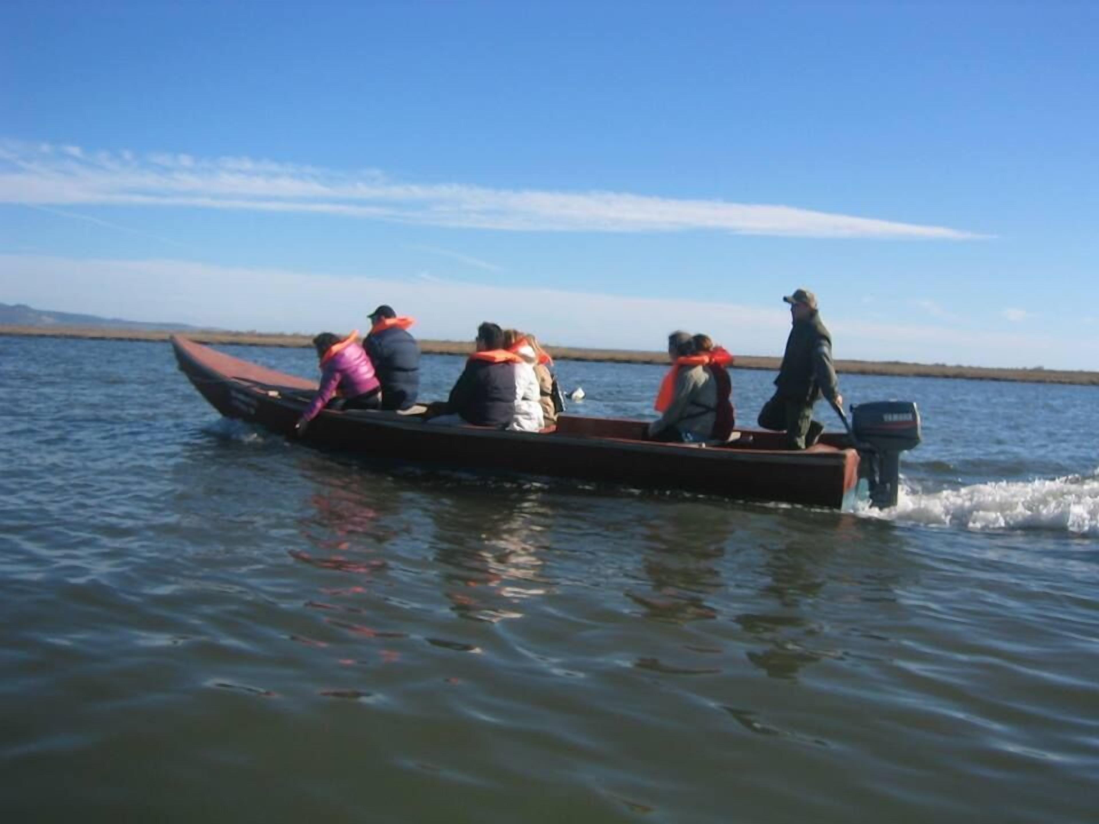 Un gruppo di persone su una barca a motore in un'acqua calma.