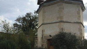 A stone building with a wooden door and a small garden area with a wooden fence. - Le Colombier de la Graverie (Senots)