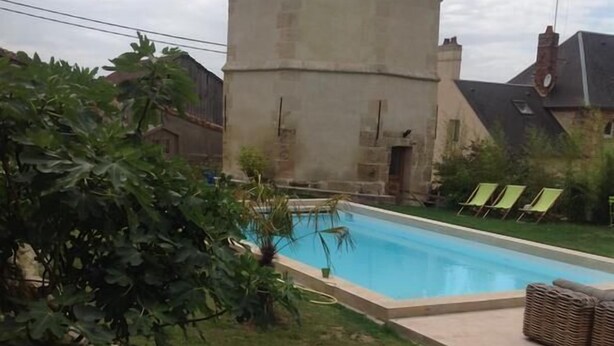 A swimming pool with a hot tub in a backyard, surrounded by greenery and a stone building. - Le Colombier de la Graverie (Senots)