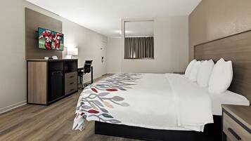 Een hotelkamer met een bed, een televisie, een bureau en een spiegel.