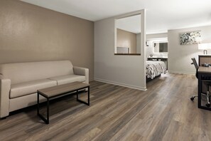 A modern living room with a sofa, a coffee table, and hardwood flooring. - Red Roof Inn & Suites Monroe, NC (Monroe)