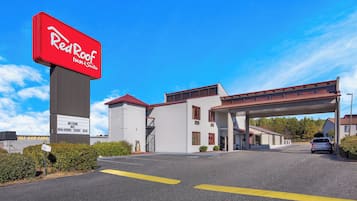 A Red Roof Inn & Suites with a clear sky, a parking lot, and a building with a red roof.