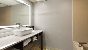 A modern bathroom with a white sink, mirror, and a bathtub. - Red Roof Inn & Suites Monroe, NC (Monroe)