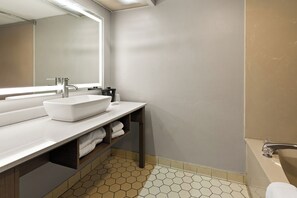 A modern bathroom with a white sink, mirror, and a bathtub. - Red Roof Inn & Suites Monroe, NC (Monroe)