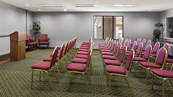 Un salón de conferencias con filas de sillas, un atril y un amplio ventanal.