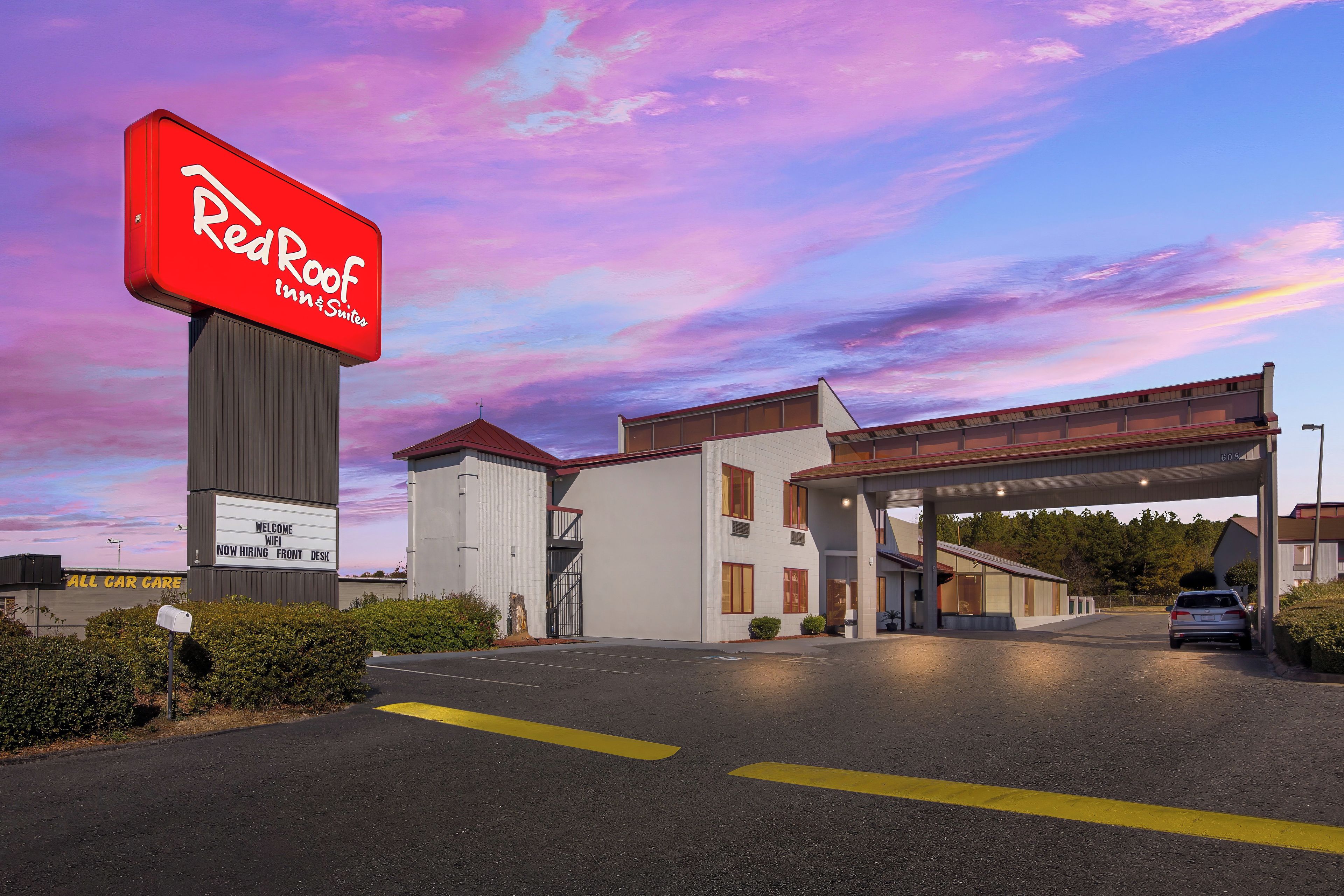 A Red Roof Inn & Suites with a clear sky and a welcoming sign.