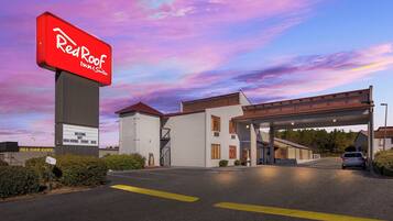 A Red Roof Inn & Suites with a clear sky and a welcoming sign.
