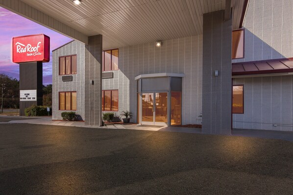 Un Red Roof Inn & Suites con un diseño moderno, que presenta un llamativo letrero de Red Roof, ventanas grandes y una entrada acogedora.