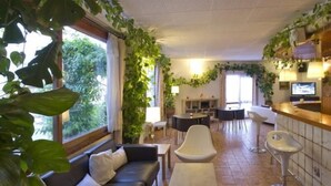 Un salon moderne avec un canapé, une table basse et un coin bar avec des tabourets. On y trouve également un téléviseur et une cheminée.