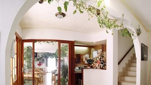 Un vaste espace de vie avec une grande porte-fenêtre coulissante donnant sur une terrasse extérieure, un escalier et un coin repas.