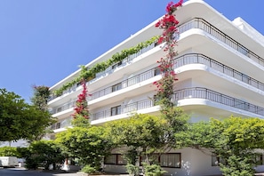 Un hôtel à plusieurs étages, doté de balcons et entouré de verdure et d’arbres.