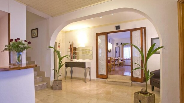 Un hall d’entrée spacieux, doté d’un sol en marbre, d’un comptoir de réception et d’un espace repas visible à travers une porte en arc de cercle.